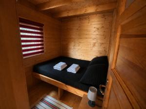 a small room with a black bed in a wooden cabin at Domekwroznowiepl in Rożnów