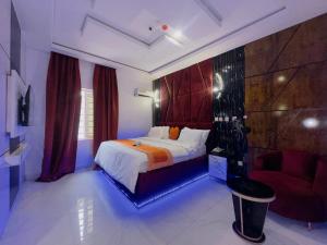 a bedroom with a large bed and a red chair at Don Marble Hotel And Suites in Auchi