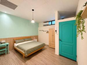 a bedroom with a bed and a green door at 巷弄內的老宅27 in Pingtung City