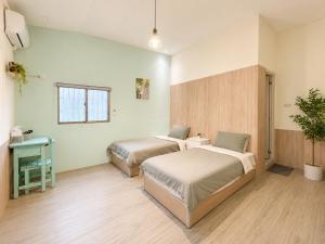 a bedroom with two beds and a potted plant at 巷弄內的老宅27 in Pingtung City