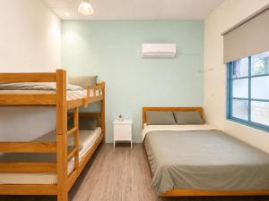 a bedroom with two bunk beds and a window at 巷弄內的老宅27 in Pingtung City