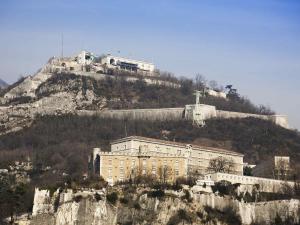 a building on top of a mountain with a train on it at ibis Styles Grenoble Centre Gare in Grenoble
