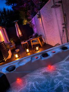 a hot tub with lights in a backyard at night at L'Écrin de la Sapinière in Merville