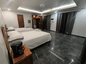 a hotel room with two beds and a television at Frontera Stay Don Pinto in Canoa Abajo