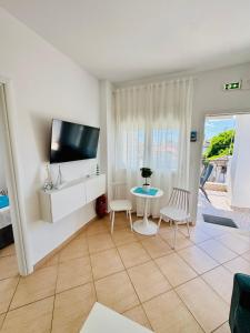 a living room with a tv and a table and chairs at MG Sea View Apartments & Private Parking in Pefkochori