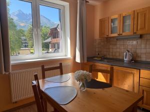 a kitchen with a wooden table and a window at Quota 850 in Tatranská Lomnica