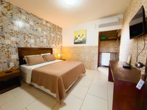 a bedroom with a bed and a desk and a television at Jardim dos Orixás in Canoa Quebrada