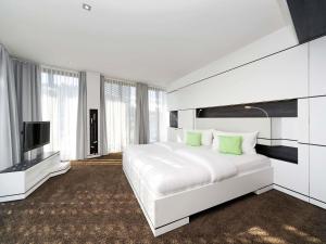 a white bedroom with a large bed and a flat screen tv at ibis Styles Nagold-Schwarzwald in Nagold +63 photos