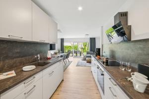 a kitchen with white cabinets and a wooden floor at Ferienwohnung Aquamarin Büsum in Westerdeichstrich +28 photos
