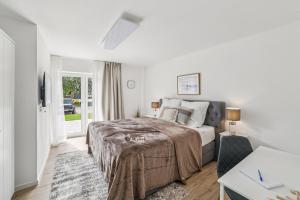 a white bedroom with a bed and a desk at Ferienwohnung Aquamarin Büsum in Westerdeichstrich
