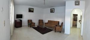 a living room with a couch and chairs and a tv at Maison indépendante pieds dans l'eau in Sousse