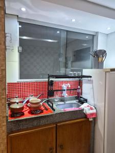 a kitchen with a sink and two pots on a stove at Flat Região Central 2 in Barbacena +3 photos