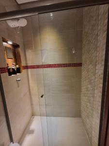 a shower with a glass door in a bathroom at Flat Região Central 2 in Barbacena