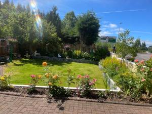 a rainbow over a garden with flowers and plants at 4 Glenfalloch Road in Crianlarich +3 photos