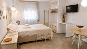 a white bedroom with a bed and a table at Est 1852 - Cozy in Andros