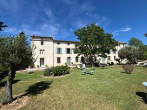 a large white building with tables and chairs in a yard at Logis Hôtel Château De Palaja in Carcassonne
