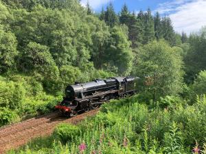 a black train is traveling down the tracks at 4 Glenfalloch Road in Crianlarich