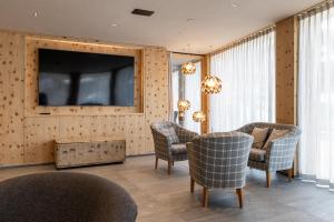 a living room with chairs and a television on a wall at Hotel Spol - Adults only in Livigno