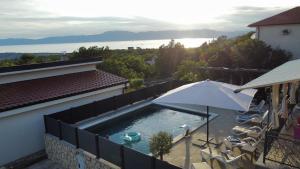 a swimming pool with an umbrella next to a house at Apartman Kata in Šmrika