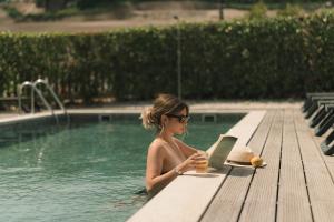 a woman sitting in a swimming pool with a laptop at Constance Retreat - Douro Verde by FERO in Constance