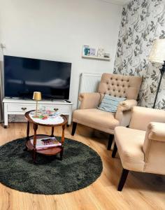 a living room with a tv and two chairs and a table at De kleine Bongerd -The little Orchard in Hengelo