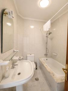 a white bathroom with a tub and a sink at Hotel Santa Clara in Monforte de Lemos