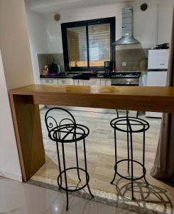 a kitchen with a wooden counter with two bar stools at Pearl Beach Apartment in Monastir