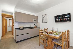 a kitchen with a wooden table and a kitchen with white cabinets at Rochebrune Apartments in Ski Resort in Claviere