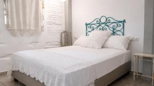 a white bedroom with a bed with a blue headboard at Est 1852 Andros - Tower 1 in Lámira