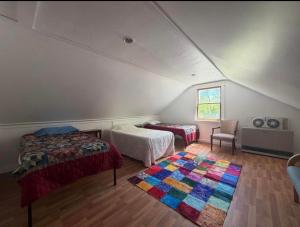 a attic bedroom with two beds and a rug at Leapin leanas in Monson