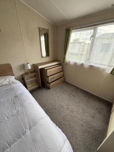 a bedroom with a bed and a dresser and a window at Seaview Holiday Rentals - Etchingham in Chestfield +7 photos