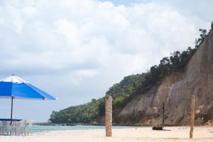 a beach with an umbrella and chairs on the sand at Bora Bora Temporada in Gamboa