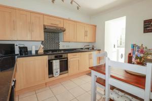 a kitchen with wooden cabinets and a stove top oven at Tin Lantern Cottage in Redruth