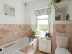 a bathroom with a tub and a toilet and a window at Tin Lantern Cottage in Redruth +11 photos