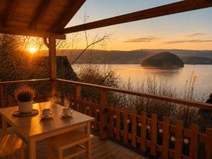 a table on a porch with a view of a lake at Domekwroznowiepl in Rożnów +5 photos