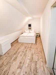 a white bedroom with a bed and a wooden floor at Mikes Fewo in Hohegeiß +19 photos