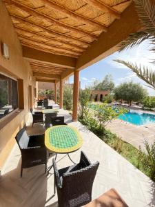 an outdoor patio with tables and chairs and a pool at Auberge Famille Benmoro in Skoura