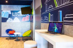 a workspace with a desk with a laptop and two stools at Ibis Budget Mulhouse Centre Gare in Mulhouse