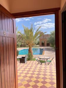 a door leading to a patio with a table and a pool at Auberge Famille Benmoro in Skoura