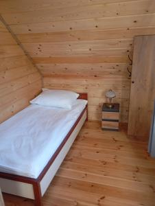 a bedroom with a bed in a wooden room at Domek Szumi las in Białowieża