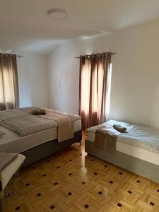 a bedroom with two beds and a wooden floor at Apartma Viković II in Njiverce