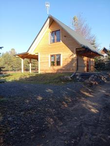 a wooden house with a porch on a field at Domek Szumi las in Białowieża