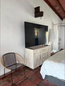 a bedroom with a tv and a bed and a chair at La Calita de Teques in Tequesquitengo