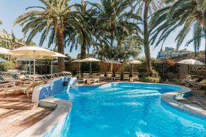 a pool with chairs and umbrellas and palm trees at Giardino Eden Resort in Ischia Town