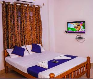 a bedroom with a bed with a tv on the wall at Hotel SAI GRAND in Mangalore