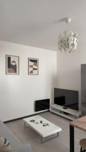 a white living room with a tv and a table at appartement de 45 m sur cour centre ville de morez in Morez