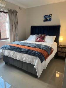 a bed with a blue headboard in a bedroom at Indigo Nest in Edgemead