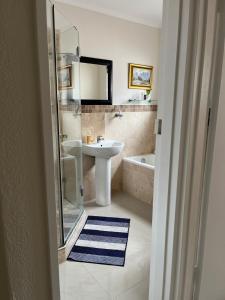 a bathroom with a sink and a shower and a tub at Indigo Nest in Edgemead +8 photos