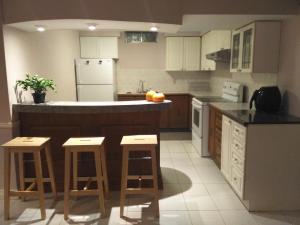 a kitchen with a counter and stools in it at Cozy Family Suite, entire place with two beds, pravite washroom and kitchen in Markham