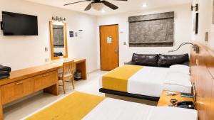 a bedroom with two beds and a desk and a television at Hotel Maioris El Diez Culiacan in Culiacán
